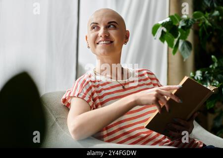 Eine fröhliche kahlköpfige Frau entspannt sich auf einer Couch, taucht in ein Buch ein und schätzt ihre Umgebung. Stockfoto