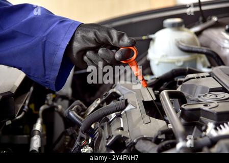 Der Mechaniker zieht die Steuerstange für den Ölstand im Fahrzeugmotor heraus Stockfoto