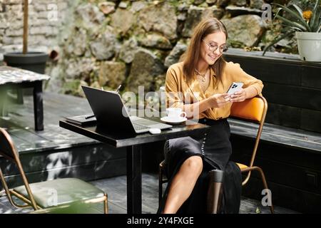 Eine junge Frau mit einer Beinprothese lächelt, während sie ihr Telefon benutzt, umgeben von der lebhaften Atmosphäre eines gemütlichen Cafés. Stockfoto