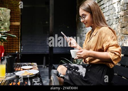 In einem lebhaften Café schlürft eine junge Frau mit einem künstlichen Bein Kaffee und blättert durch ihr Telefon, um alltägliche Momente zu genießen. Stockfoto