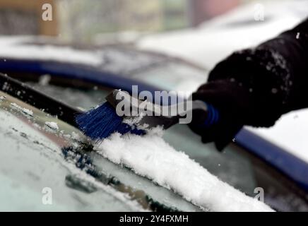 Entfernen von Schnee von der Windschutzscheibe des Autos. Reinigen Sie das Autofenster im Winter vom Schnee. Stockfoto