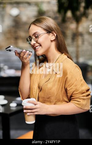 Eine junge Frau hält glücklich eine Kaffeetasse, während sie in einem Café am Telefon plaudert. Stockfoto