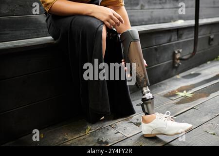 In einem gemütlichen Café nimmt sich eine junge Frau einen Moment Zeit, um sich zu entspannen und ihr künstliches Bein selbstbewusst zu umarmen. Stockfoto