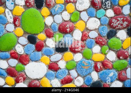 Viele Kieselsteine und Steine in verschiedenen Farben bemalt. Wanddekoration. Stockfoto