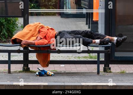 Ein heimatloser Mann schläft in einer Straßenbahnhaltestelle, Ein betrunkener Mensch liegt in einer Straßenbahnhaltestelle und schläft seinen Rauschgift aus Stockfoto