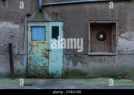 Eine alte Tür, wo die Farbe abblättert, alte Tür, verlassene Plätze, eine alte blaue Industrietür mit abblätternder Farbe, schwarz-weiß Stockfoto