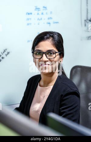Geschäftsfrau mittleren Alters lächelt selbstbewusst an ihrem Arbeitsplatz. Ihr positiver Ausdruck und ihr professionelles Verhalten im Unternehmensumfeld. Stockfoto