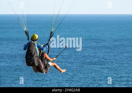 Gleitschirmfliegen in Phuket Thailand mit blauem Himmel. Männer, die hoch oben am Himmel mit wunderschöner Landschaft fliegen. Entdecken Sie Phuket vom Himmel aus. Thailand Absatz Stockfoto