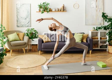 Eine engagierte junge Frau mit Anorexie betreibt Yoga zu Hause und konzentriert sich auf ihre Gesundheit und ihr Wohlbefinden, während sie von Pflanzen umgeben ist. Stockfoto