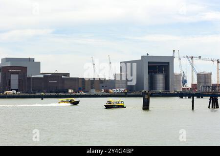 Zwei Wassertaxis auf der Nieuwe Maas im Frachthafen Rotterdam. Rotterdam, Niederlande - 9. Juli 2004: Zwei Wassertaxis auf der Nieuwe Maas im Frachthafen Rotterdam. Einige Lagerhäuser, Tanks und Silos im Hintergrund. Edit netherlands rotterdam INDUSTRIAL Port B97A6708 Stockfoto