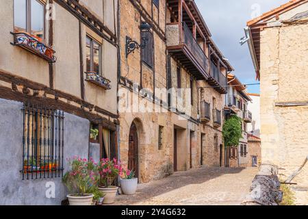 Malerische Straße mit traditionellen, mit Blumen dekorierten Gebäuden in einer ländlichen Stadt. Frías, Provinz Burgos, Spanien Stockfoto