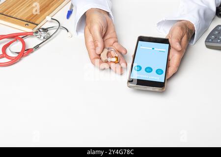 Arzt mit Hörgerät und Smartphone mit Smart Control App auf weißem Hintergrund. Stockfoto