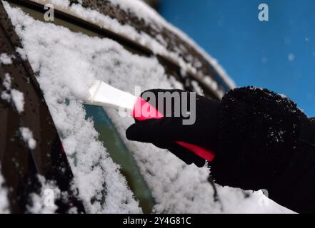 Schneeräumung von der Autoscheibe. Entfernen von Schnee von der Windschutzscheibe. Stockfoto