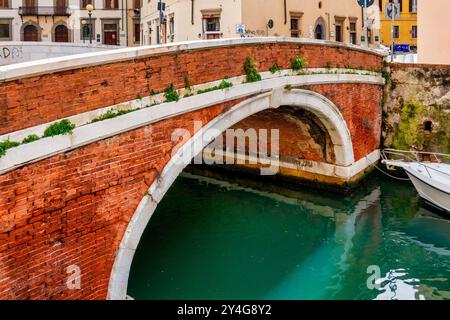 Ponte di Marmo, eine historische Brücke aus Backstein und Stein in Livorno, Italien, die über einen Kanal im alten Hafenviertel der Stadt spannt. Stockfoto