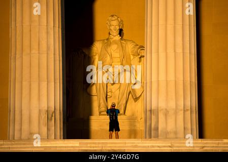 WASHINGTON DC, USA – die Statue von Abraham Lincoln im Lincoln Memorial wird kurz nach Sonnenaufgang von natürlichem goldenem Sonnenlicht beleuchtet. Dieser Lichteffekt, der rund um die Frühlings- und Herbstnachtgleiche sichtbar ist, unterstreicht die Pracht des Denkmals, wenn die Sonne durch den östlichen Eingang scheint. Das Lincoln Memorial befindet sich in der National Mall und ist eines der berühmtesten Denkmäler der USA. Hinweis: Farbe und Beleuchtung sind natürlich. Stockfoto