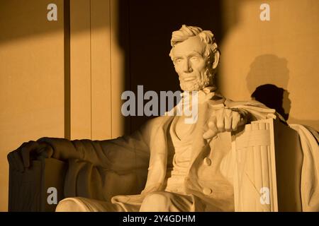 WASHINGTON DC, USA – die Statue von Abraham Lincoln im Lincoln Memorial wird kurz nach Sonnenaufgang von natürlichem goldenem Sonnenlicht beleuchtet. Dieser Lichteffekt, der rund um die Frühlings- und Herbstnachtgleiche sichtbar ist, unterstreicht die Pracht des Denkmals, wenn die Sonne durch den östlichen Eingang scheint. Das Lincoln Memorial befindet sich in der National Mall und ist eines der berühmtesten Denkmäler der USA. Hinweis: Farbe und Beleuchtung sind natürlich. Stockfoto