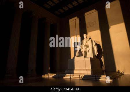 WASHINGTON DC, USA – die Statue von Abraham Lincoln im Lincoln Memorial wird kurz nach Sonnenaufgang von natürlichem goldenem Sonnenlicht beleuchtet. Dieser Lichteffekt, der rund um die Frühlings- und Herbstnachtgleiche sichtbar ist, unterstreicht die Pracht des Denkmals, wenn die Sonne durch den östlichen Eingang scheint. Das Lincoln Memorial befindet sich in der National Mall und ist eines der berühmtesten Denkmäler der USA. Hinweis: Farbe und Beleuchtung sind natürlich. Stockfoto