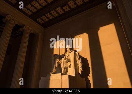 WASHINGTON DC, USA – die Statue von Abraham Lincoln im Lincoln Memorial wird kurz nach Sonnenaufgang von natürlichem goldenem Sonnenlicht beleuchtet. Dieser Lichteffekt, der rund um die Frühlings- und Herbstnachtgleiche sichtbar ist, unterstreicht die Pracht des Denkmals, wenn die Sonne durch den östlichen Eingang scheint. Das Lincoln Memorial befindet sich in der National Mall und ist eines der berühmtesten Denkmäler der USA. Hinweis: Farbe und Beleuchtung sind natürlich. Stockfoto