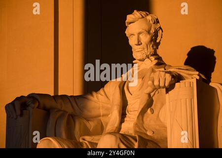 Lincoln Memorial Statue Golden Light Close Up / WASHINGTON D.C., Vereinigte Staaten — Daniel Chester French sitzt Lincoln, geformt aus weißem Georgia Marmor, leuchtet bernsteinfarben, während das dunkle Morgenlicht in der Nähe der Frühlingskundnachtgleiche über das Gesicht der Statue schwingt. French entwarf die 5,8 m hohe Figur so, dass sie vom offenen östlichen Eingang der Kammer leuchtend erscheint – ein bewusster optischer Effekt, der bei der Eröffnung der Gedenkstätte im Jahr 1922 in die Architektur integriert wurde. Stockfoto