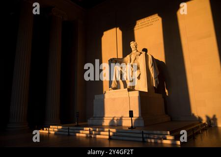 WASHINGTON DC, USA – die Statue von Abraham Lincoln im Lincoln Memorial wird kurz nach Sonnenaufgang von natürlichem goldenem Sonnenlicht beleuchtet. Dieser Lichteffekt, der rund um die Frühlings- und Herbstnachtgleiche sichtbar ist, unterstreicht die Pracht des Denkmals, wenn die Sonne durch den östlichen Eingang scheint. Das Lincoln Memorial befindet sich in der National Mall und ist eines der berühmtesten Denkmäler der USA. Hinweis: Farbe und Beleuchtung sind natürlich. Stockfoto