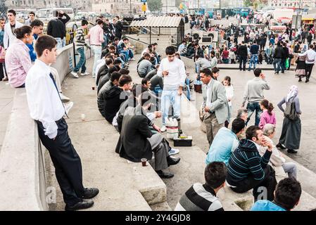 Eminönü Waterfront Menschenmassen Istanbul Türkei // ISTANBUL, Türkei – Menschenmassen versammeln sich entlang der Eminönü Waterfront in Istanbuls Altstadt, wo viele traditionelle Fisch-Sandwiches genießen, die lokal als „balik ekmek“ bekannt sind. Die geschäftige Szene zeigt die Beliebtheit der Gegend als Lokal und Touristenattraktion am Ufer des Goldenen Horns. Stockfoto