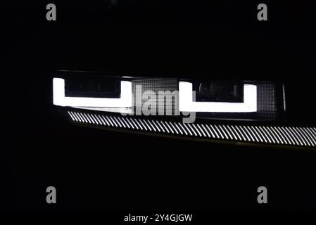 Aktivierte Scheinwerfer eines modernen Autos. Nachts fotografiert. Fahrzeugscheinwerfer. Nahaufnahme der Scheinwerferlampe. Detail auf der Außenseite des Fahrzeugs. Stockfoto