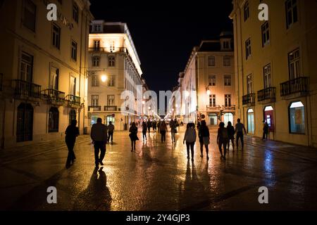 Rua Augusta Fußgängerstraße bei Nacht Lissabon Portugal // LISSABON, Portugal – die Rua Augusta, eine Fußgängerstraße im historischen Zentrum von Lissabon, wird abends von kunstvollen Straßenlaternen beleuchtet. Die Durchgangsstraße verbindet den Fluss Tejo mit dem Hauptgeschäftsviertel der Stadt und dient als primäre Fußgängerroute durch das Stadtviertel Baixa. Straßenlaternen säumen den kopfsteingepflasterten Fußweg, der von traditioneller portugiesischer Architektur flankiert wird und Geschäfte und Cafés beherbergt. Rua Augusta ist Teil des Wiederaufbaus der Innenstadt von Lissabon nach dem Erdbeben von 1755 in Pombaline. Stockfoto