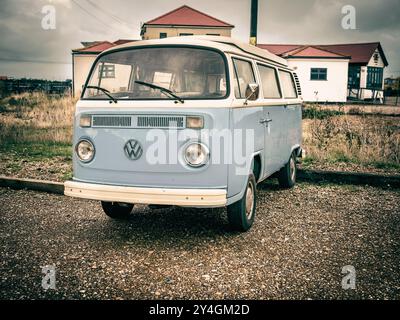 Ein klassischer blauer Volkswagen Campervan parkt in Dungeness, gleich vor dem Eisenbahnrestaurant in einem dunklen und stimmungsvollen Vintage-Stil Stockfoto