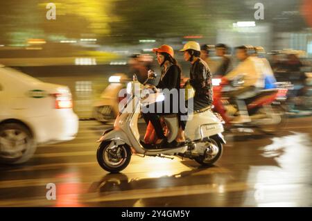 HANOI, Vietnam – Motorroller und Fahrräder drängen sich am Abend auf eine enge Straße in Hanois Altstadt. Die belebte Szene zeigt das chaotische, aber lebendige Straßenleben, das typisch für Hanoi ist, während die Einheimischen die geschäftigen Straßen mit dem Motorrad oder dem Fahrrad erkunden. Stockfoto