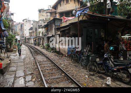 HANOI, Vietnam – Bahngleise führen durch ein altes Viertel in Hanoi, wobei die Gleise sehr nahe an die umliegenden Gebäude schmiegen. Die berühmte Bahnstraße ist ein bekannter Teil der Stadt, wo der Zug nur wenige Zentimeter von Häusern und Geschäften in der engen Gasse entfernt vorbeifährt. Stockfoto