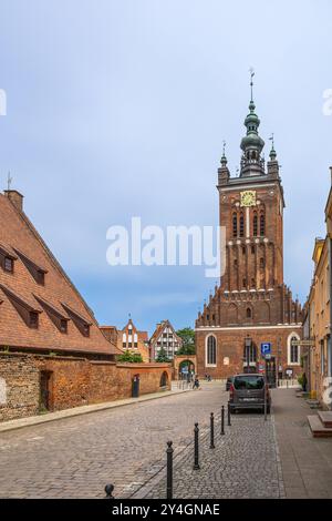 Das historische kleine Mühlengebäude und der Uhrenturm der Katharinenkirche in Danzig, Polen, zeigen beide traditionelle Backsteinarchitektur. Stockfoto