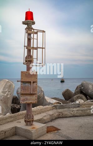 Der rote Schiffsanzeiger befindet sich am Ende des Wellenbrechers am Eingang zur Castro Marina in Apulien, Italien. Stockfoto