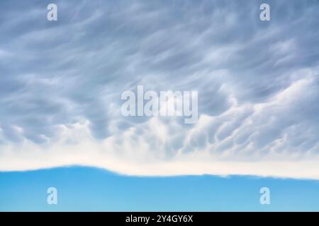 Mammatus wolkt sich über einem klaren Himmel im horizontalen Format. Ende des Sturms Stockfoto