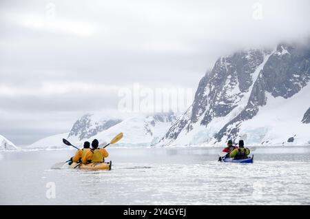 Kajak Petermann Island Antarktis / PETERMANN ISLAND, Antarktis — zwei Kajakfahrer paddeln mit einem Tandemkayak durch die eisigen Gewässer rund um Petermann Island, im Wilhelm Archipel südlich des Lemaire Channel vor der westlichen Antarktischen Halbinsel. Die Insel ist ein beliebter Ausflugsziel, bekannt für ihre sich überschneidenden Adélie- und Gentoo-Pinguinkolonien und für den historischen Steinhaufen auf dem Megalestris-Hügel, der als Antarctic Treaty Historic Site und Monument No. 27 bezeichnet wird und Jean-Baptiste Charcot die Überwinterung der Pourquoi-Pas kennzeichnet? Bei Port Beschneidung im Jahr 1909. Kajakausflüge bieten den Besuchern Stockfoto