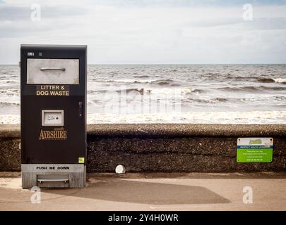 Ein Abfalleimer und eine Holzbank neben einem geparkten Auto vor Sanddünen am Strand in Ayr in Schottland während eines windigen Sommers im Jahr 2024 Stockfoto