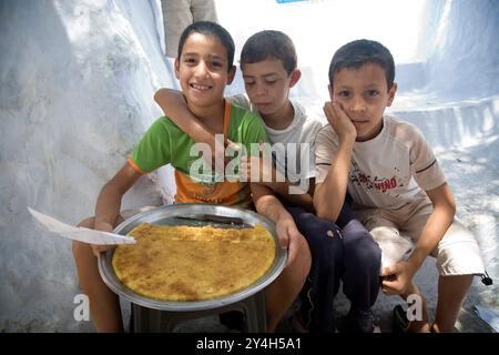 Chefchaouen, Marokko, 3. Juli 2007, drei Kinder sitzen glücklich und präsentieren ihre hausgemachten Kuchen zum Verkauf in Chefchaouen, die lokale Unternehmergeist zeigen Stockfoto