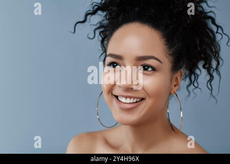 Abgeschnittenes Studio-Porträt einer lächelnden Frau mit schwarzem Lockenhaar Stockfoto