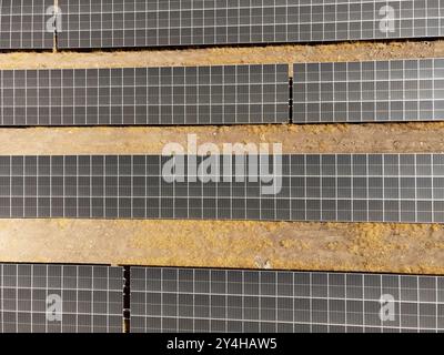 Eine Drohne erfasst aus der Luft Reihen von Solarpaneelen, die in einem ländlichen Feld installiert sind, und zeigt nachhaltige Energielösungen für eine umweltfreundlichere Zukunft Stockfoto