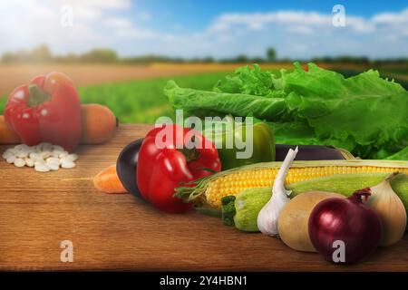 Buntes Gemüse, einschließlich Paprika, Salat und Mais, auf einem Holztisch mit malerischem Hintergrund. Perfekt für Konzepte der gesunden Ei Stockfoto