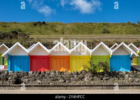 Scarborough, Großbritannien. Eine Reihe von farbenfrohen Strandchalets oder Hütten an der Promenade an der North Bay. Eine traditionelle englische Küstenszene Stockfoto