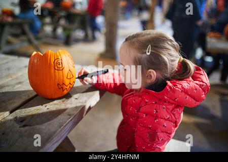 Niedliches Mädchen im Vorschulalter macht Jack-o-Laterne für Halloween Stockfoto