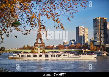 Touristenboot schwimmt in der Nähe des Eiffelturms und der Grenelle-Brücke mit Freiheitsstatue an einem hellen Herbsttag in Paris, Frankreich Stockfoto