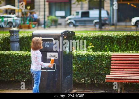 Vorschulmädchen sammelt Müll auf der Straße von Helsinki, Finnland, und packt ihn in eine Müllkiste Stockfoto