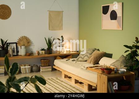 Mittelgroße komfortable Couch mit drei Kissen und Bambustablett mit Teekanne in der Ecke des geräumigen Wohnzimmers Stockfoto