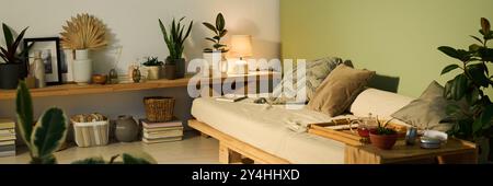 Lange Belichtung einer mittelgroßen komfortablen Couch mit drei Kissen und Bambustablett mit Teekanne in der Ecke des Wohnzimmers Stockfoto