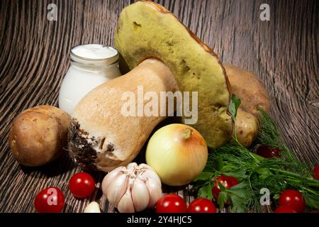 Bratpilz Boletus edulis. Zutaten zum Kochen von Braten: Große Pilze Boletus edulis, Kartoffeln, Sauerrahm, Zwiebeln, Knoblauch, Tomaten, Knoblauch Stockfoto