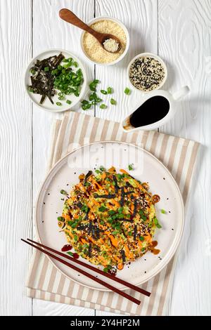 Vegetarisches Okonomiyaki, japanischer Pfannkuchen mit Kohl, mit Sriracha-Mayo bestreut mit Nori, Sesamsamen, Zwiebeln auf Teller mit ch Stockfoto