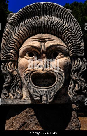 Mit Blick auf die römische Theatermaske, die heute im römischen Theater in Ostia Antica, Italien, ausgestellt wurde und einst Teil der architektonischen Dekoration des Theaters war. Stockfoto