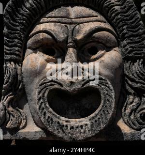 Der Mund ist weit geöffnet auf der römischen Theatermaske, die heute im römischen Theater in Ostia Antica, Italien, ausgestellt wurde und einst Teil der architektonischen Dekoration des Theaters war. Stockfoto