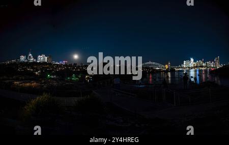 Die Menschen treffen sich an einem Aussichtspunkt, wenn der September-Supermond, auch bekannt als „Harvest Moon“, aufsteigt und den Himmel über der Skyline von Sydney erleuchtet. Stockfoto